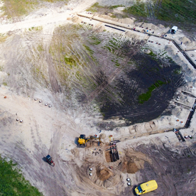 Luftaufnahme einer Baustelle mit Baggern und Erdarbeiten.