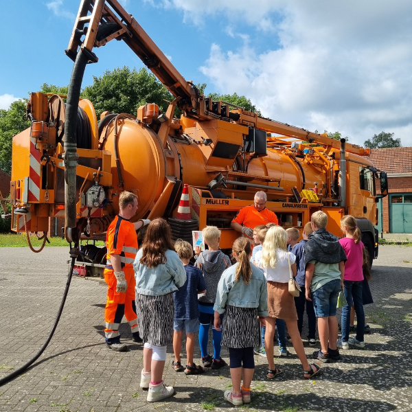 indergruppe vor einem großen, orangefarbenen Servicefahrzeug.
