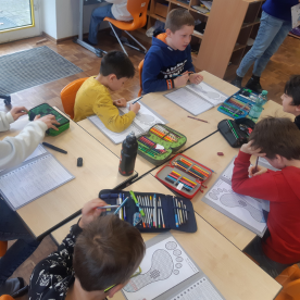 Schüler arbeiten gemeinsam an einem Tisch im Klassenzimmer mit ihren Schulmaterialien.