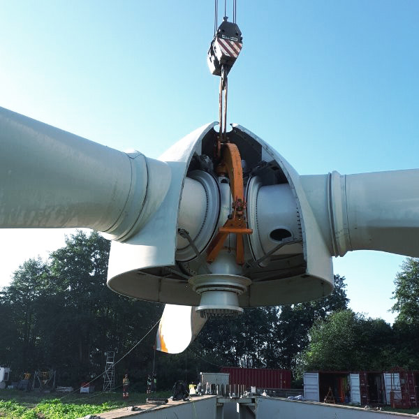 Der Rotor einer Windenergieanlage liegt am Boden auf einer Wiese und wird gewartet.