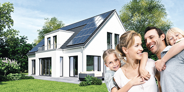 Zwei Erwachsene und ien Kind stehen vor einem weißen Haus - das Dach ist mit Photovoltaikanlagen  bestückt.