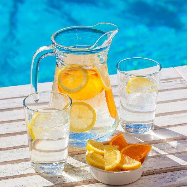Krug Zitronenwasser und Gläser am Pool.