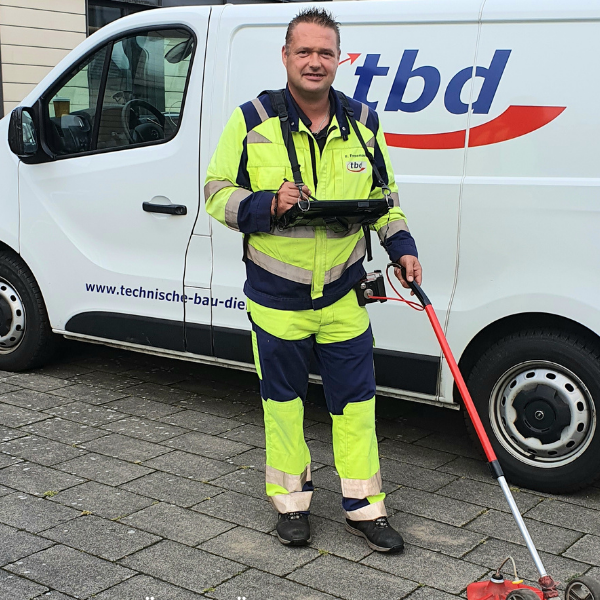 Arbeiter in gelber Schutzkleidung vor einem weißen TBD-Transporter.