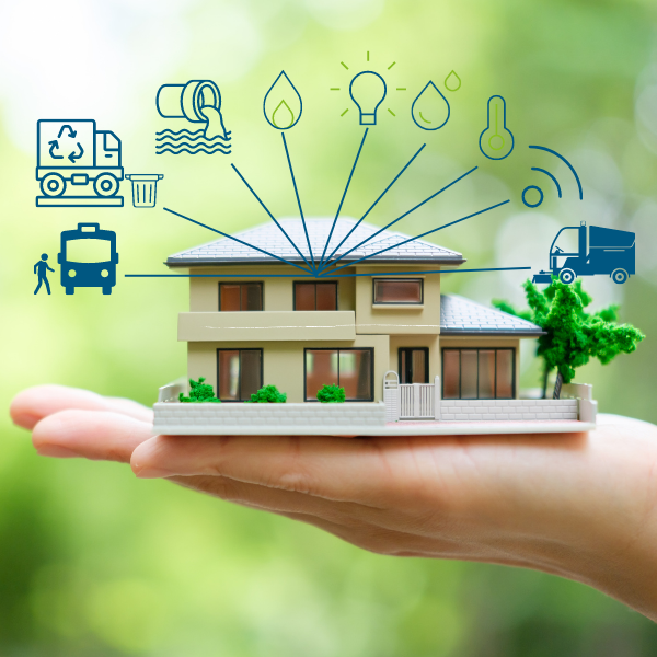 Hand hält Modellhaus mit Energiesymbolen im Hintergrund.
