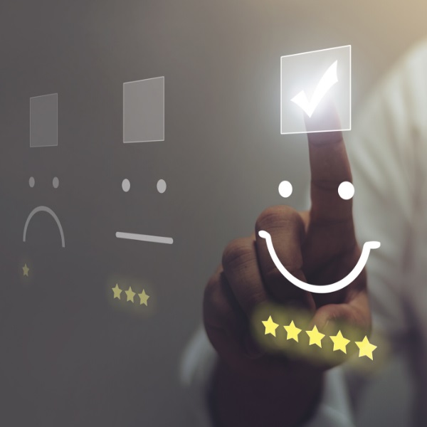 Ein Finger drückt auf einen lächelnden Smiley - darunter sind 5 gelbe Sterne zu sehen.