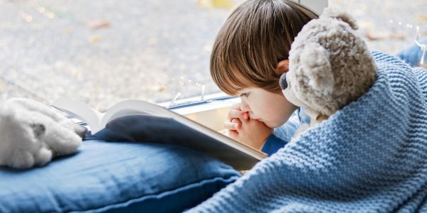 Junge wärmt sich und seine Teddy an einer Heizung